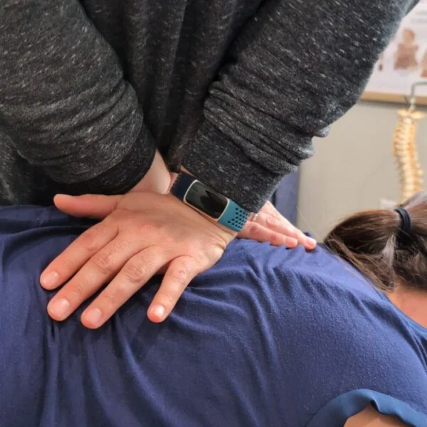Cincinnati Chiropractor Dr. Faith Swartzendruber's hands are placed on a patients back for a chiropractic adjustment.
